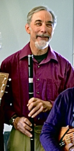 Musician of older years in purple shirt playing flue