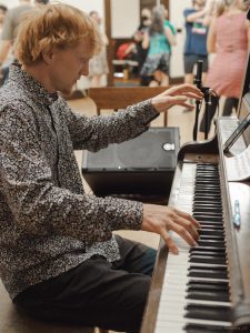 Red haired male musician playing piano at folk dance